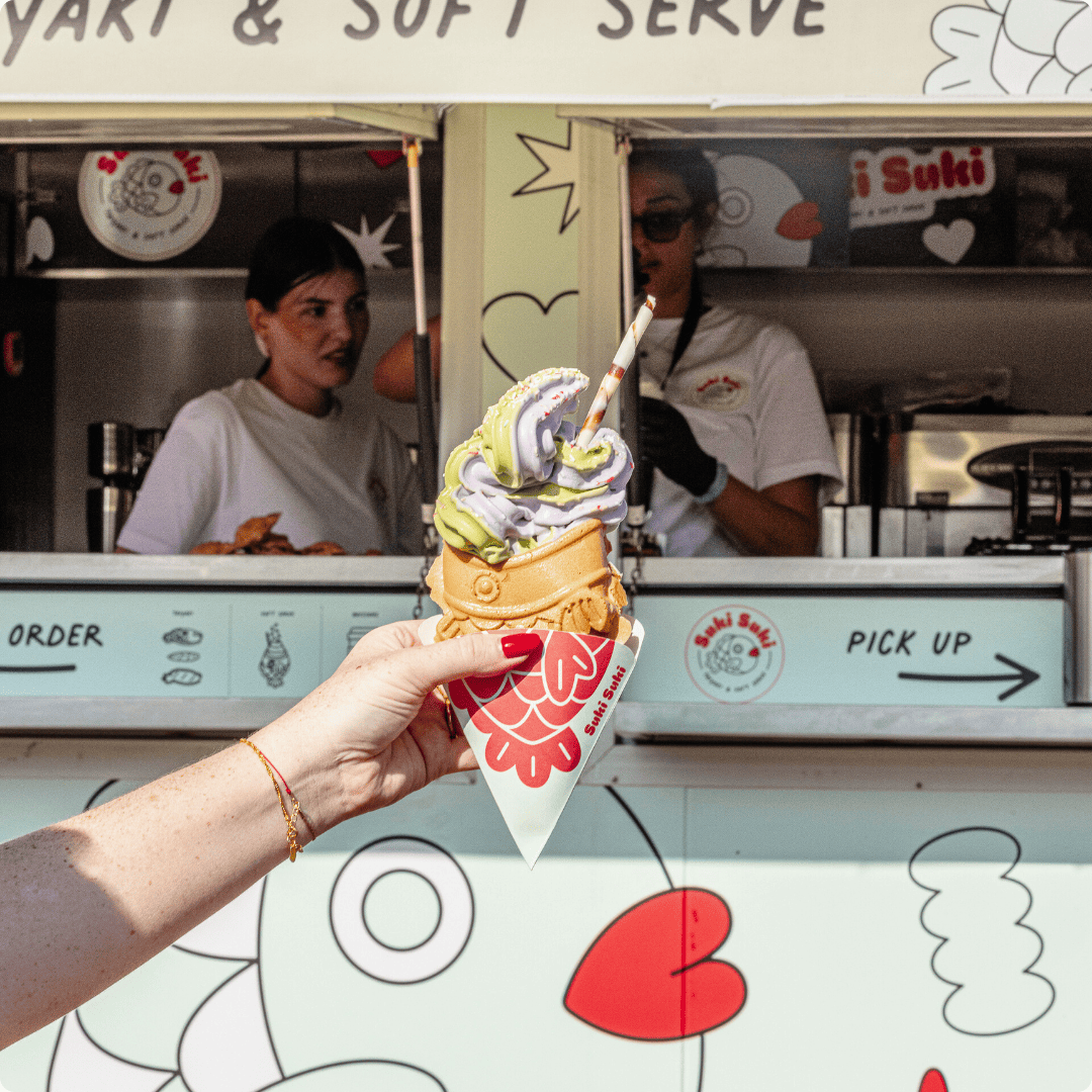 Hand holding matcha and taro taiyaki soft serve in front of the Suki Suki food truck in Switzerland